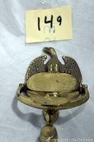 Front view image of heavy brass eagle door knocker showing detailed eagle wings and body with knocker handle beneath.