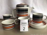 Full set of vintage German coffee/tea items including kettle, two cups with saucers, creamer, and sugar bowl with black, orange, white stripe pattern.