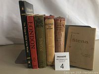 Front view of 5 books standing upright showing titles: The Penguin Atlas of the World, London, Rome, Italian Central Italy 1925, and Siena postcards booklet.