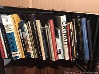 Photo of art books in a box, various titles visible including Lecture by Oktay Aslanapa, House of Oracles, Gotchai, Paris Living Rooms, and more