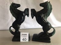 Pair of blue-green glazed ceramic horse bookends shown upright side by side on white background with ruler card showing lot number.