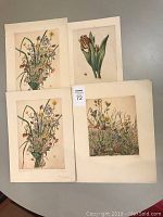 Four hand-painted floral etching prints displayed on a table showing variation in size and floral composition.