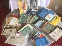 Overview of various vintage railway books, manuals, and ephemera spread on a table showing a wide assortment of titles and colors.