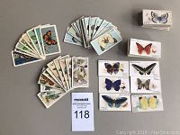 Full display of the assortment of butterfly and moth cigarette and tea cards spread on a flat surface.