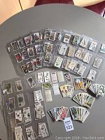 Full view of the approx 300 cards arranged on a table, many in plastic sleeves, showing various botanical illustrations of flowers and plants.