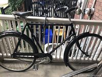 Left-side view of bicycle on porch showing frame, saddle, handlebars, wheels