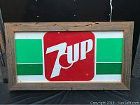 Full view of framed vintage 7UP tin sign showing logo and color pattern