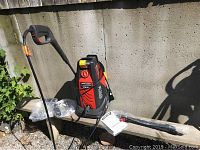 Full view of Black & Decker pressure washer with spray wand and accessories laid out on bench outdoors in sunlight.