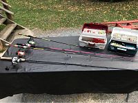 Four fishing poles laid out on a table with two open tackle boxes showing fishing tackle inside.