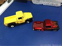 Top view of two diecast trucks, yellow 1956 Ford and red 1955 Chevrolet Stepside with flame decals