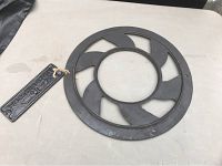 Top view of circular cast iron floor grate with 6 curved spokes and open center.