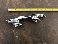 Full side view of the chrome leaping Jaguar hood ornament with a tape measure indicating about 6 inches in length
