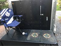 Photo showing two Toronto Maple Leafs floor mats placed on a black surface with a Toronto Maple Leafs lawn chair and blue and white fuzzy dice nearby.