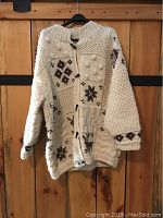 Front view of cream colored Mary Maxim sweater showing brown snowflake, deer, and tree patterns with toggle buttons