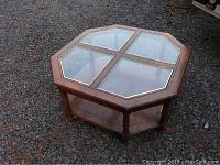 Octagonal coffee table with four glass sections on top, medium-brown wood finish, brass trim around glass.