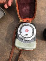 Front view of the first vintage General Electric PR-1 light meter in leather case showing dial and GE logo