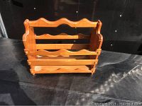 Front view of wooden magazine rack showing curved slats and wooden structure