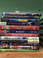 Photo showing a stacked set of 13 DVDs with cases in various genres including animation, action, thriller and family films.