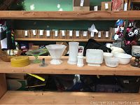 Photo of mixed glassware lot on wooden table shelf, includes carnival glass and milk glass pieces of various shapes and sizes.