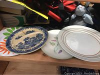 View of seven assorted decorative plates stacked showing different patterns including blue Willow and floral designs