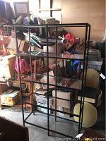 Front view of the black enamel metal frame shelving unit filled with various items in background