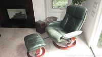 Chair and ottoman placed near fireplace and window, front view showing both pieces