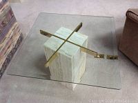 Top view of the square beveled glass table top and goldtone cross supports above granite base