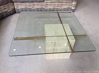 Top view showing clear 36x36 inch beveled glass top with goldtone metal cross supports and square granite base underneath