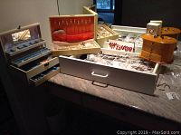 Various open jewelry boxes displaying costume jewelry such as bracelets, necklaces, rings, pins, and earrings.