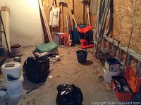 Overview of shed interior showing floor with various yard and pool supplies including buckets, bags, and tools scattered on the floor beneath metal shelving unit.