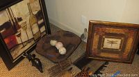 Two framed pictures, wooden animal faces, elephant figurine, and table runner arranged on carpeted floor close to corner of room