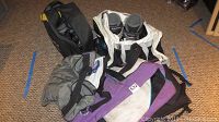 Photo showing the Salomon ski boots with straps and two ski carriers on carpeted floor.