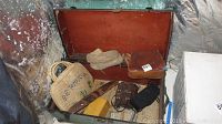 Vintage metal steamer trunk with assorted items inside, located in basement corner