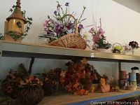 Shelf displaying the fall-themed floral arrangements made with grapevine pumpkins, dried leaves, small pumpkins, and mixed fall decor items.