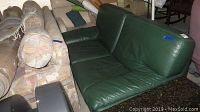 Front-side angle view of green leather loveseat showing overall design and cushion alignment