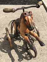 Front view of the wooden horse tricycle showing horse head, wooden handles, and front metal wheel.
