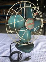 Front view of Electrohome vintage metal fan showing blue blades and white wire cage with center logo badge.