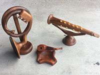 Photo showing all three wood-carved pieces together: circular tuba, clarinet on stand, and pipe with ashtray.