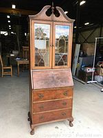 Front view of entire antique walnut secretary desk with closed hutch doors and drop-down desk front raised