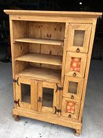 Front view of the pine display unit showing open shelving, glass inset drawer fronts and metal pulls.