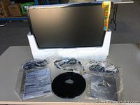 ASUS 21.5-inch LCD monitor out of the box with power cables, video cable, stand base, and manuals spread on table.