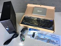 All components displayed together: desktop tower, keyboard in box, cables, manual