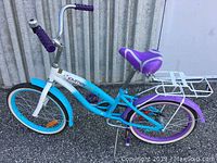 Full side view of the "Journey Girls" bicycle showing blue and purple frame, white wall tires, and rear rack