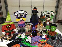 Various Halloween decorations including witches, Frankenstein, pumpkin, and Happy Halloween metal signs displayed on a table.