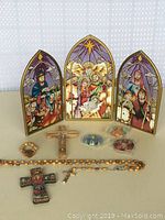 Photo showing the entire religious lot with the colored glass triptych, crucifix, rosary and religious magnets.
