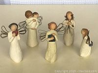 Five Willow Tree angel figurines displayed side by side showing various poses and objects held.
