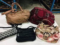 Overview of four purses in the lot showing variety of material and color.