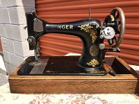 Front view of vintage Singer sewing machine with gold ornate detailing mounted on a wooden base.