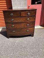 Front view of vintage mahogany bow front chest of drawers with 5 drawers and brass handles.