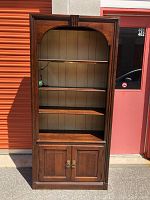 Front view of Pennsylvania House wooden bookcase with three shelves, cupboard with closed doors, showing design and finish.